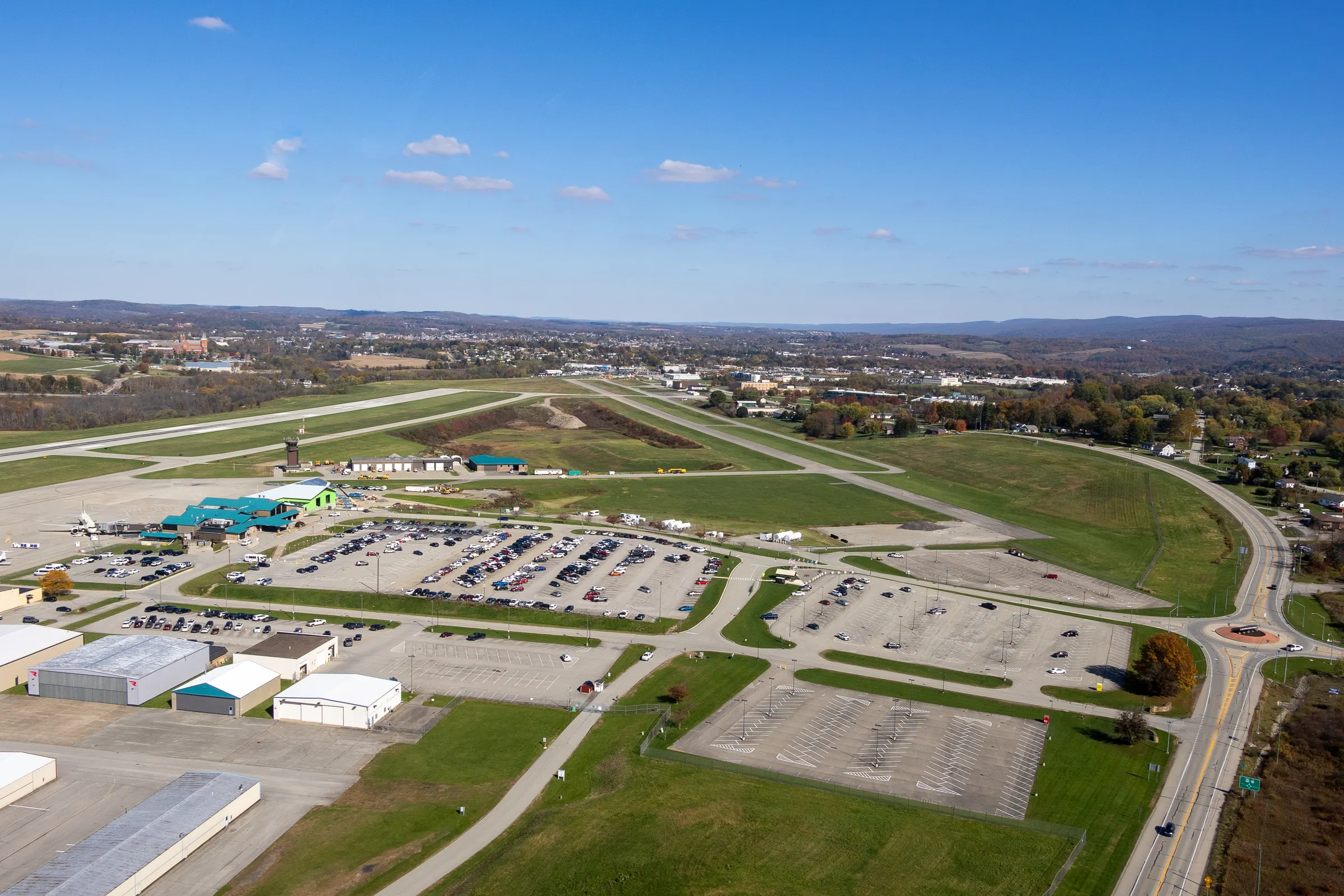 Arnold Palmer Regional Airport from the air: the terminal, the parking lots, and the runway, with the ridges beyond