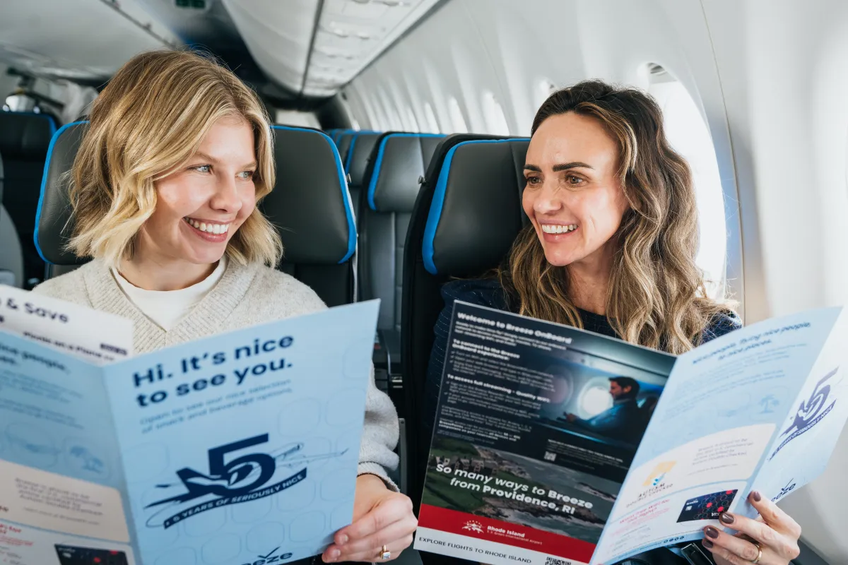Two friends laughing over the onboard menu in their window seats