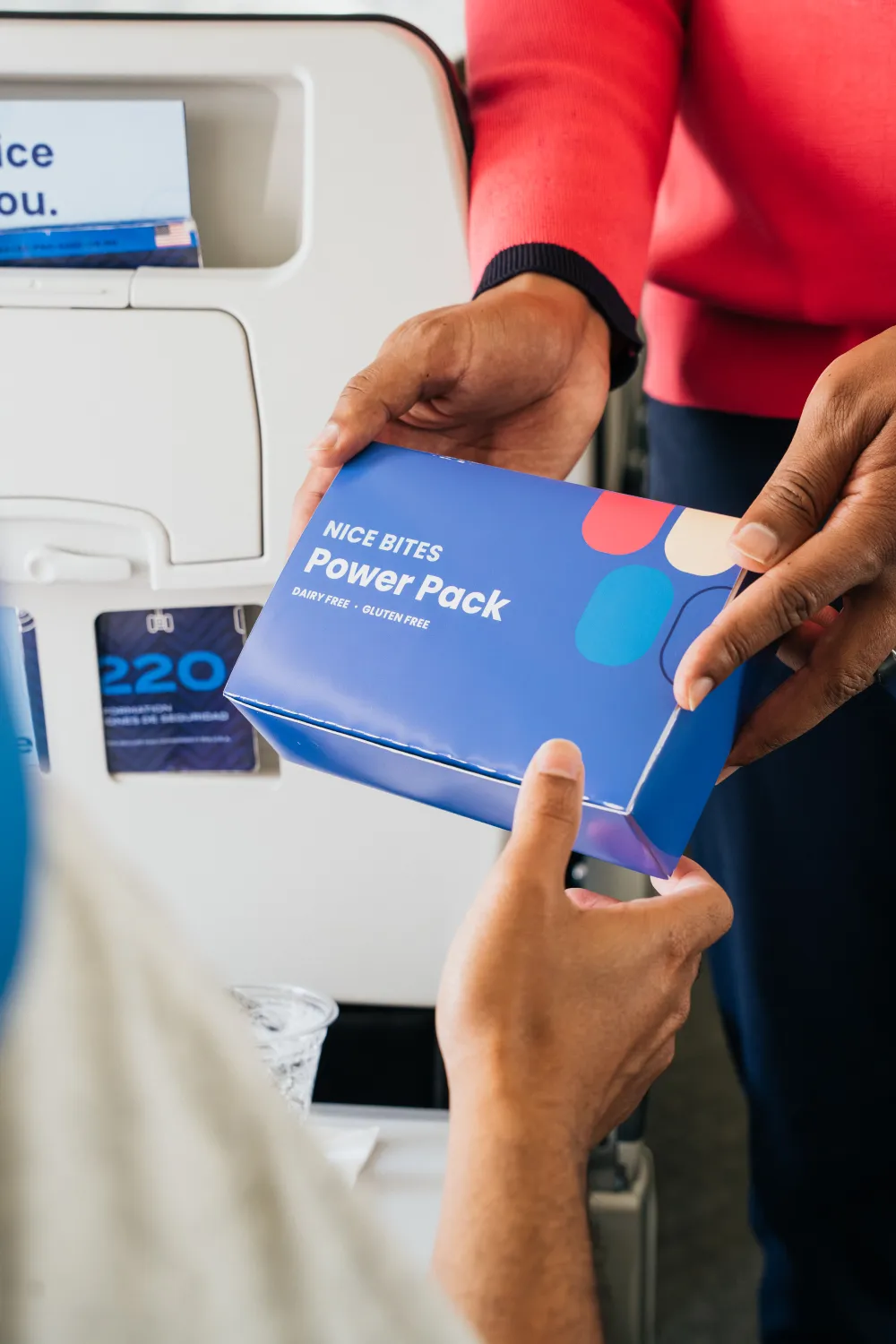 A flight attendant handing over a boxed snack
