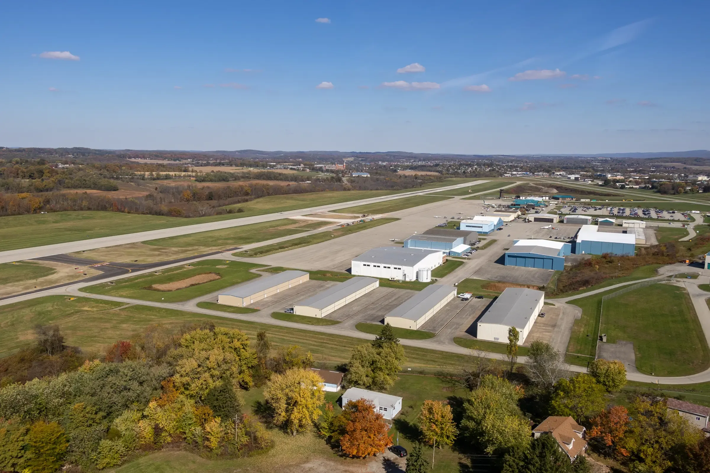The hangar rows and runway at Arnold Palmer Regional Airport from the air, with fall color in the trees
