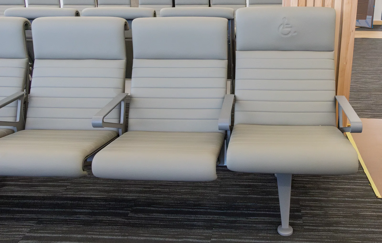 A row of gate-area seats, with an accessible seat marked by the wheelchair symbol at the end of the row