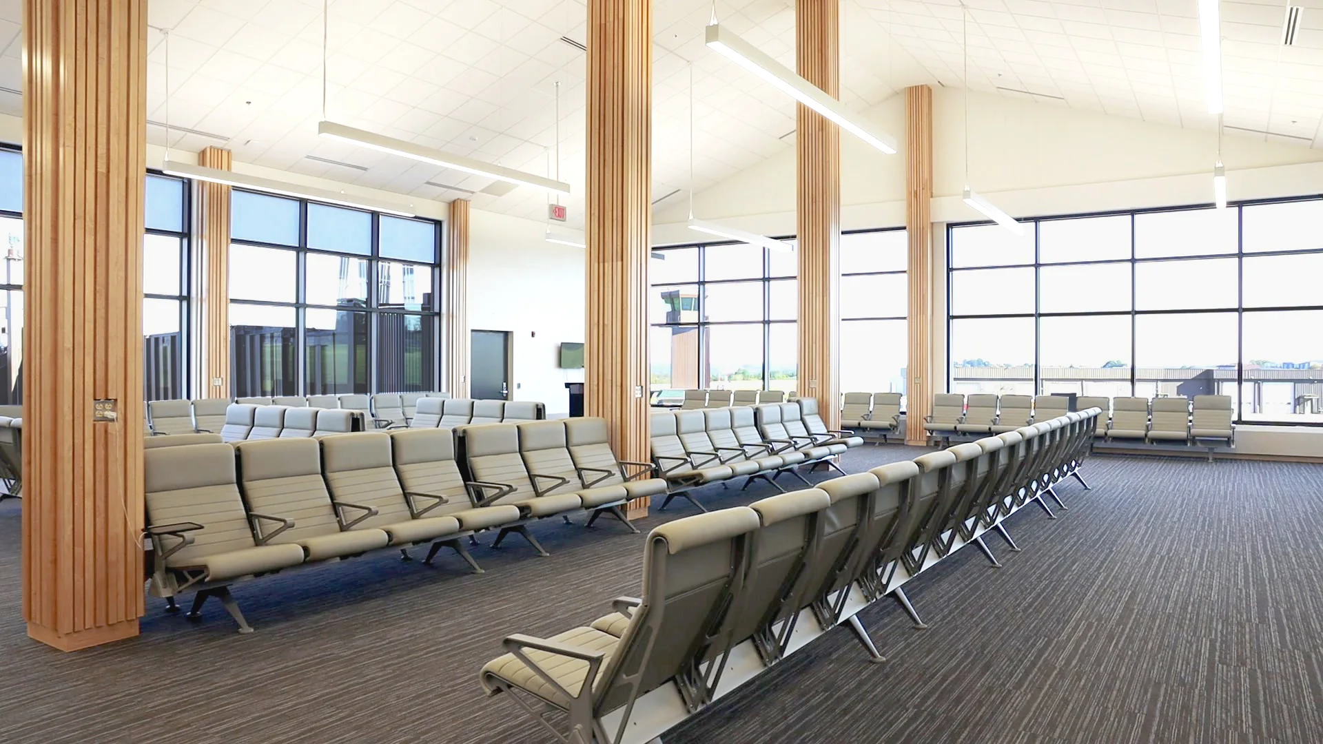 The new gate area, with rows of seating, wood-clad columns, and floor-to-ceiling windows