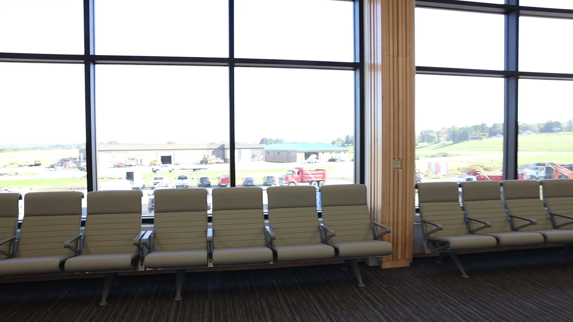 Gate-area seats lined up along the window wall, with a view out to the hangars and airfield